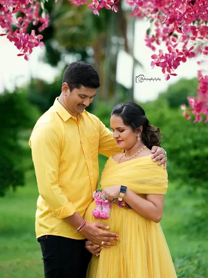 A cute gender reveal shot with the couple holding pink baby shoes in a garden setting.