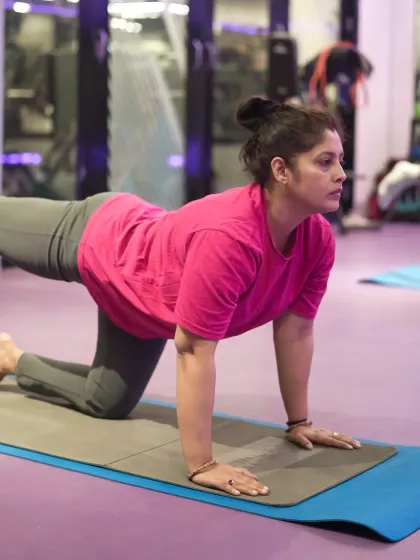 A close-up of a member practicing the Balancing Table Pose. This posture is great for improving stability and core strength, and the image highlights her concentration and proper alignment.