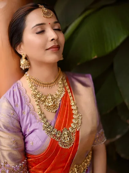 A close-up of our client Anusha, serene and beautiful on her engagement day. The rich temple jewelry perfectly complements the intricate zari work on her lavender and red silk saree.