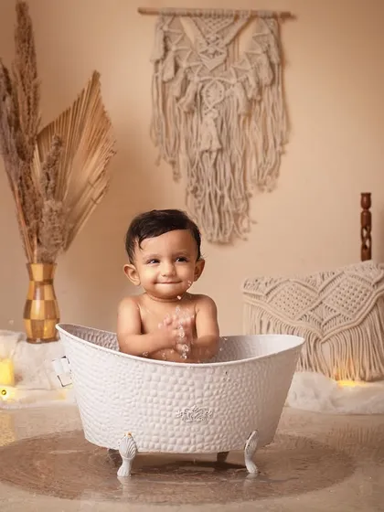 It's time for a morning bath! A happy baby enjoys a splash in a classic clawfoot tub in our cozy boho setup.