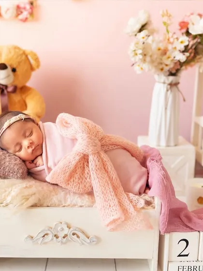 A dreamy newborn portrait with the baby sleeping on a miniature bed, surrounded by teddy bears and soft pink decor. Every detail is carefully planned.
