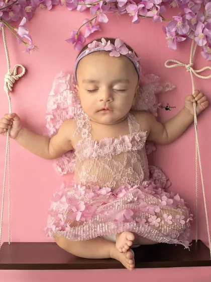 A little angel dreaming on a swing. This creative setup with delicate wings and a floral theme adds a touch of fantasy to a classic newborn session.