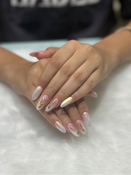 Elegant and ethereal, this set features a pearly, iridescent chrome base with delicate gold butterfly stickers. The shimmer on these long almond nails is absolutely dreamy.