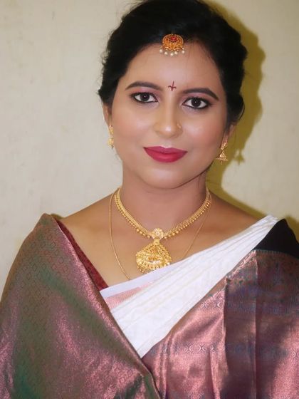 A simple yet elegant muhurtham makeover. The makeup is natural and radiant, with a classic red lip and a simple bindi, perfect for a bride who wants a timeless and understated look.
