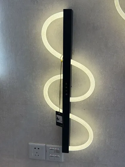 A modern, serpentine LED wall light. This fixture creates a dynamic, flowing line of light on the wall, perfect for a contemporary space.