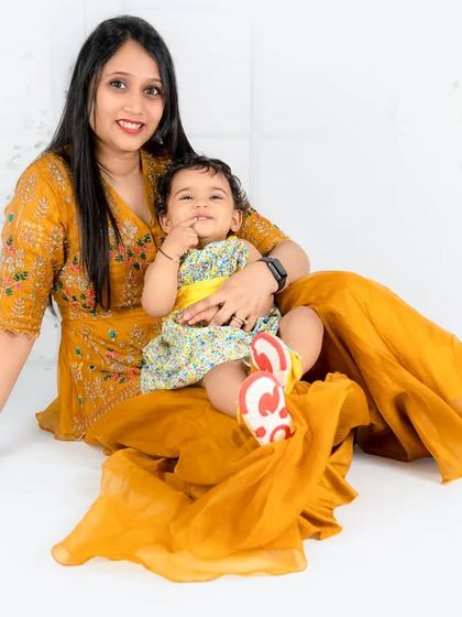 A mother and daughter in beautiful coordinating yellow outfits. The flowing fabric of the mother's dress adds a soft, artistic element to the portrait.