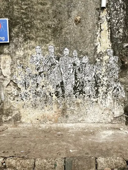 A fading paste-up artwork on a weathered wall at Sassoon Dock. This image captures the temporary and evolving nature of street art, which changes and decays over time.