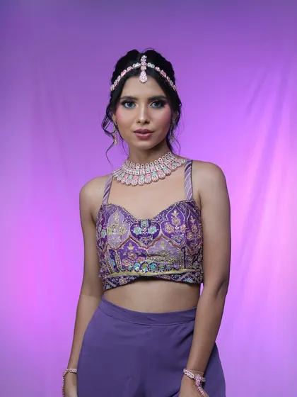 A full shot of the model against a purple background, showcasing the complete modern glam look.