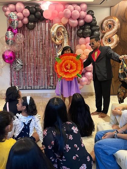 A giant flower appearing from nowhere is a great visual trick that always makes kids smile. Here I am at a house party, using colourful props to keep the young audience captivated.