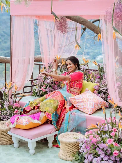 The bride seated on her Mehendi throne, surrounded by a riot of colorful flowers in Jim Corbett.