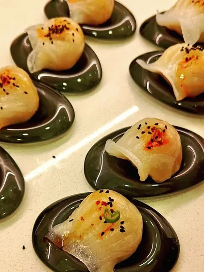 Artfully plated dim sum on individual dark green spoons. This image highlights the elegant presentation of our appetizers, perfect for a sophisticated event.