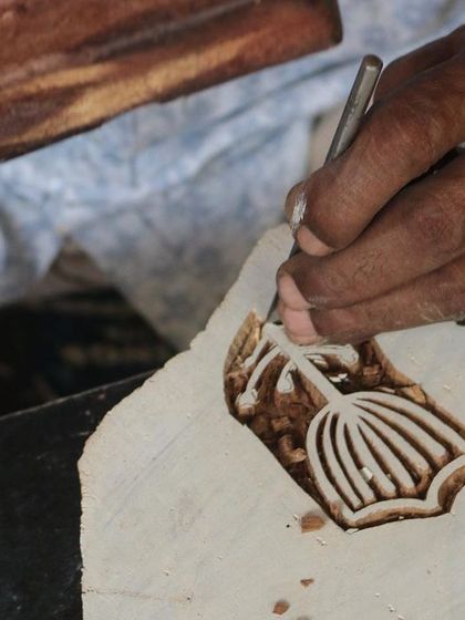 A close-up of a master carver's hands bringing a floral design to life on a teak block. This particular block was created for a collaborative workshop with the Fabric Workshop Museum in Philadelphia.