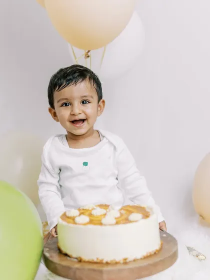 A happy baby boy enjoying his first birthday cake. The simple setup puts all the focus on his joyful expression.