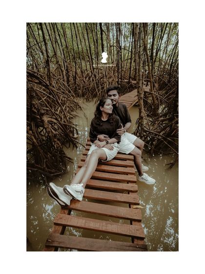 A fun and adventurous pre-wedding shoot on a wooden walkway over water. The couple's casual outfits and happy expressions make this feel spontaneous and joyful.