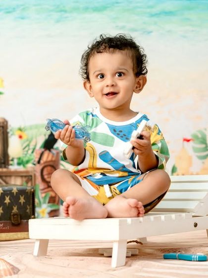 Playing with sunglasses, this little one is all smiles during his tropical beach session.