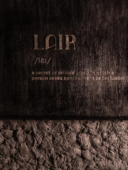 The definition of "Lair" etched into the wall, a direct statement of the brand's identity.