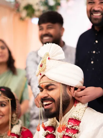 A fun, candid moment as the groom's nose is playfully pulled, a common ritual in some Indian weddings.