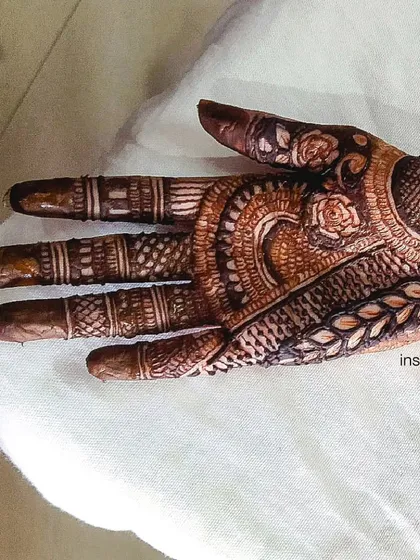 This is a detailed look at the palm of a traditional design. You can see the fine line work, shading, and different motifs like roses and leaves that come together to create a rich texture.