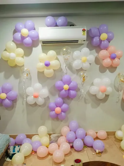 For a softer, more whimsical look, I can create these flower-shaped balloon arrangements on the wall. Using pastel colors like lavender, peach, and cream, this style is a sweet and charming option for an anniversary surprise.