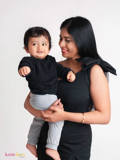 A stylish mother and son portrait. Dressed in modern black outfits, the mother looks lovingly at her son, creating a chic and tender image.