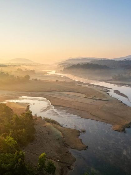 A misty sunrise over the Sharavathi River valley. This aerial shot captures the layers of fog settling between the hills, a common and beautiful sight in the region.
