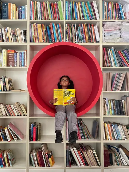 We designed this floor-to-ceiling library with a fun, circular reading nook built right into the shelves. Finished in a vibrant red, it creates a playful and immersive spot for a child to get lost in a book.