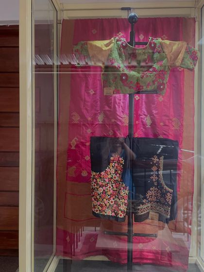 Another view of the embroidered blouses on display. These pieces showcase different styles, from delicate floral patterns to intricate Kasuti work.