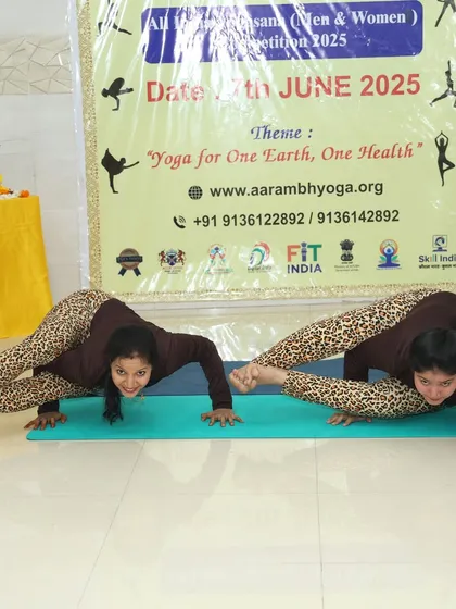 Two participants hold a synchronized arm balance pose, Mayurasana (Peacock Pose), showcasing immense core and arm strength.