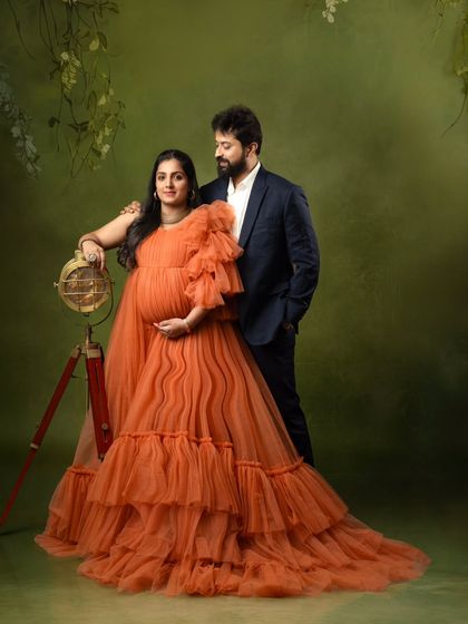 A sophisticated couple's portrait, with the partner in a suit complementing the vibrant orange gown.