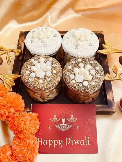 A close-up of our ornate dry fruit jars on a wooden tray, a perfect centerpiece for a Diwali gift collection.