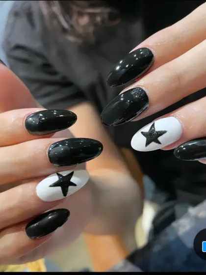 A striking monochrome design. These oval-shaped nails feature a mix of glossy black and white accent nails with a bold black star.