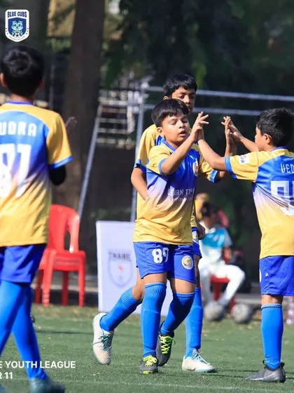 Teammates celebrating a goal with high-fives during a U11 league game.