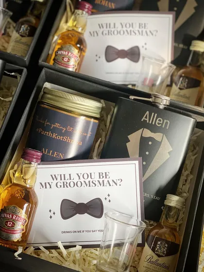 Getting the boys ready for the big day! This groomsmen hamper includes miniature bottles of Chivas Regal and Ballantine's, a personalized hip flask, a shot glass, and a custom candle.