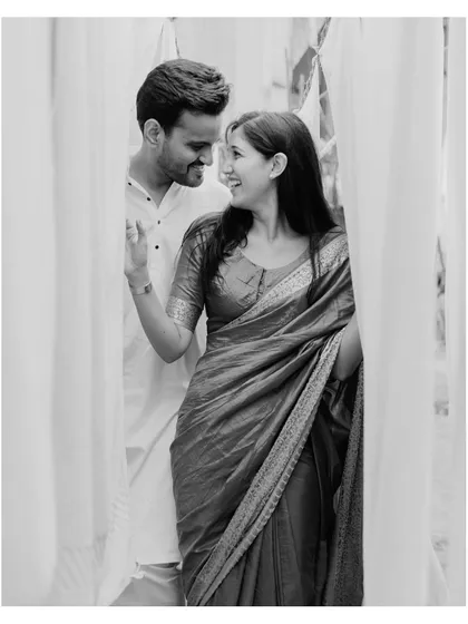A beautiful black and white close-up, capturing an intimate glance between the couple through a curtain of white fabric.