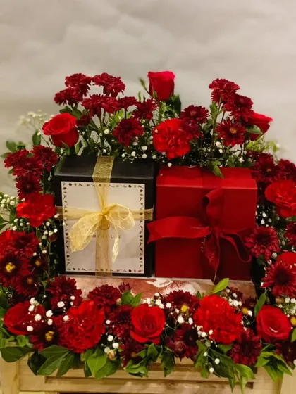 For those truly special occasions, I create luxurious floral hampers that command attention. This arrangement features rich red flowers surrounding premium gift boxes, designed to convey appreciation and high regard.