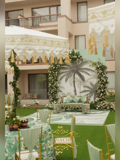 The main stage for the tropical Mehndi, featuring a backdrop with a palm tree motif, framed by white floral arches.