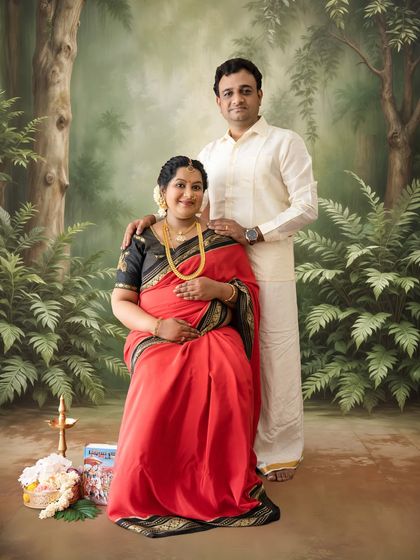 A classic family portrait pose with the couple in traditional South Indian outfits, set against a painted forest backdrop for a timeless feel.