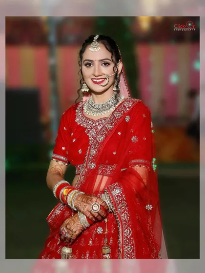 A half-length portrait of the bride in her red wedding lehenga. This shot offers a clear view of her complete look, from the traditional nath to the intricate embroidery on her outfit.