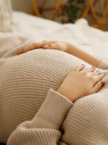 A close-up on the bump, wrapped in a cozy knit sweater. This shot is all about texture, warmth, and the intimate feeling of carrying your little one.