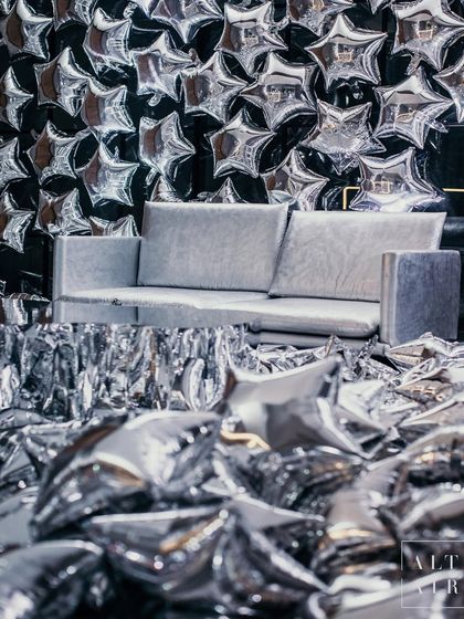 A photo booth moment from 'The Melting Disco Ball', featuring a wall of silver star balloons and a floor covered in confetti. Every corner of this event was designed to be an immersive, high-glam photo opportunity.