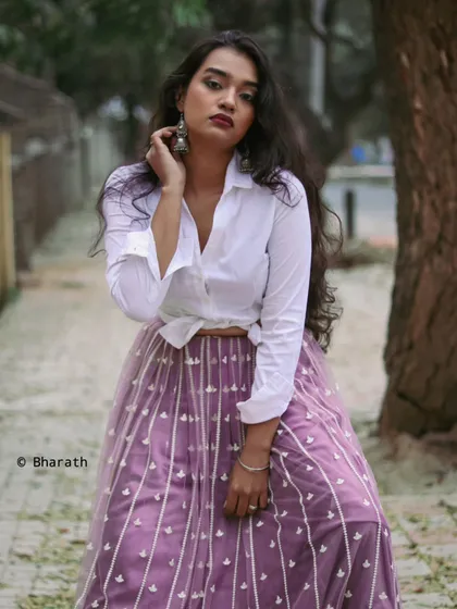 A chic fusion look combining a classic white shirt with a flowing, embroidered lavender skirt. This outdoor shot is perfect for a modern ethnic wear brand.