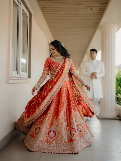 A classic twirl shot showing off the bride-to-be's stunning lehenga. The groom's admiring glance in the background adds a lovely narrative layer.