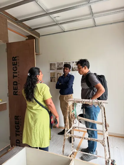 Another angle of the on-site discussion, with the raw plywood structure of the furniture visible.