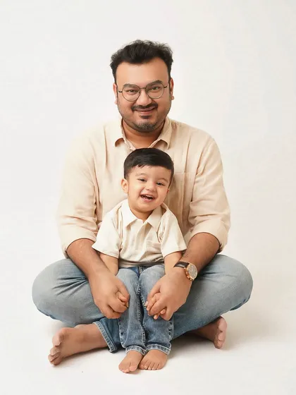 A father and son sit together, sharing a happy and relaxed moment. The simple setup and genuine smiles make this a perfect candid family portrait.