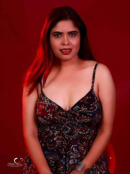 A close-up with a direct, steady gaze. The red lighting adds a touch of warmth and intensity.