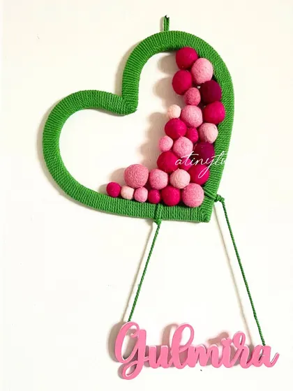 Another angle of the custom heart nameplate. The yarn-wrapped frame and hanging name add a soft, handmade touch to this personalized decor.