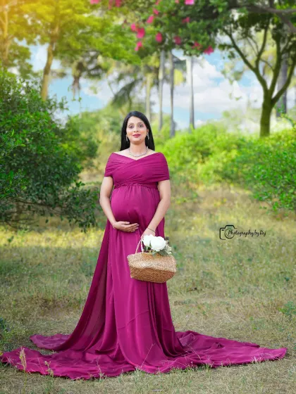 A beautiful solo portrait in a wine-colored gown, set against a lush green background. The long train of the dress adds an elegant touch.