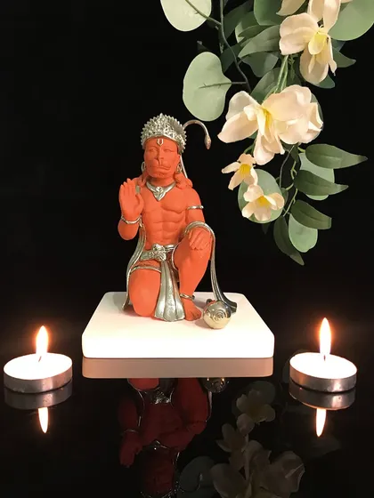Invoke strength and unwavering devotion with this exquisite Lord Hanuman idol. The vibrant orange hue and silver accents capture his powerful yet humble form, creating a focal point of positive energy.