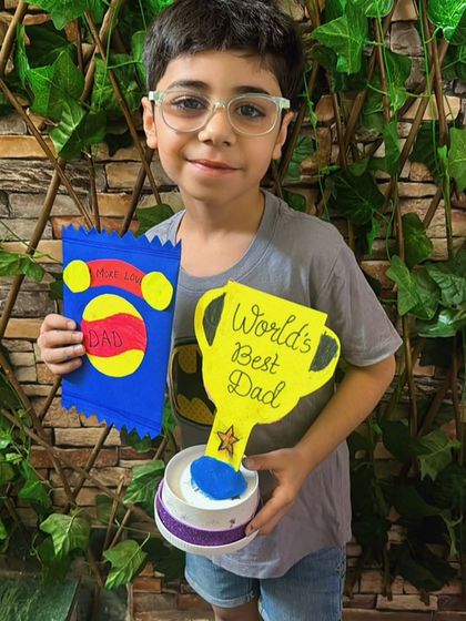 A student proudly holds up his "World's Best Dad" trophy and handmade card.