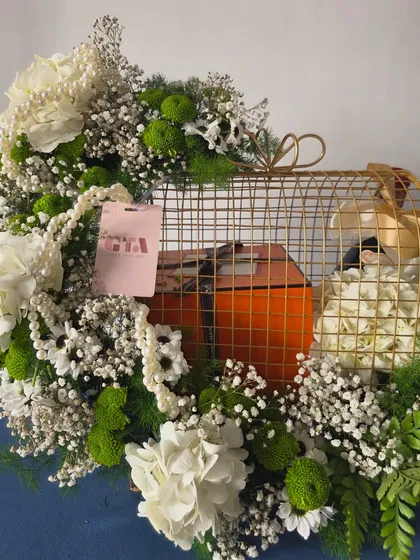 A close-up perspective focusing on the intricate floral work and the custom pink gift tag. Every element is carefully placed to feel abundant and luxurious.